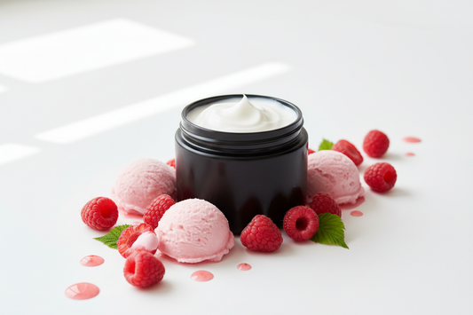 white body butter cream in a black jar surrounded by raspberries and raspberry sorbet scoops